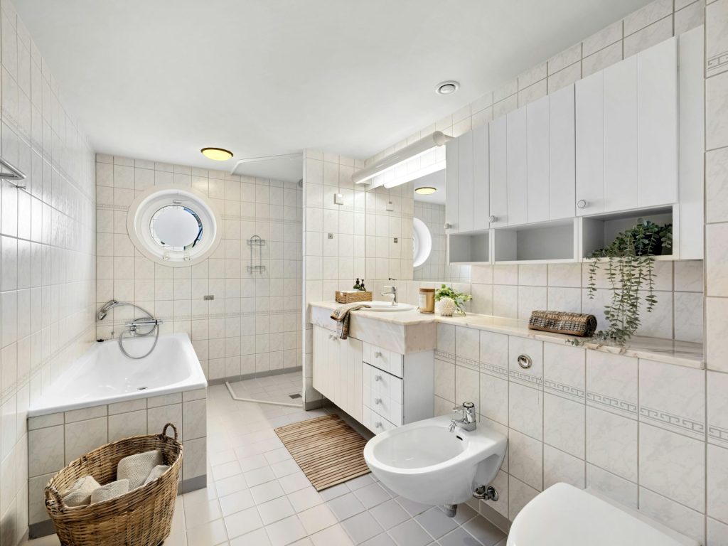A bathroom with a tub, toilet, sink, and mirror